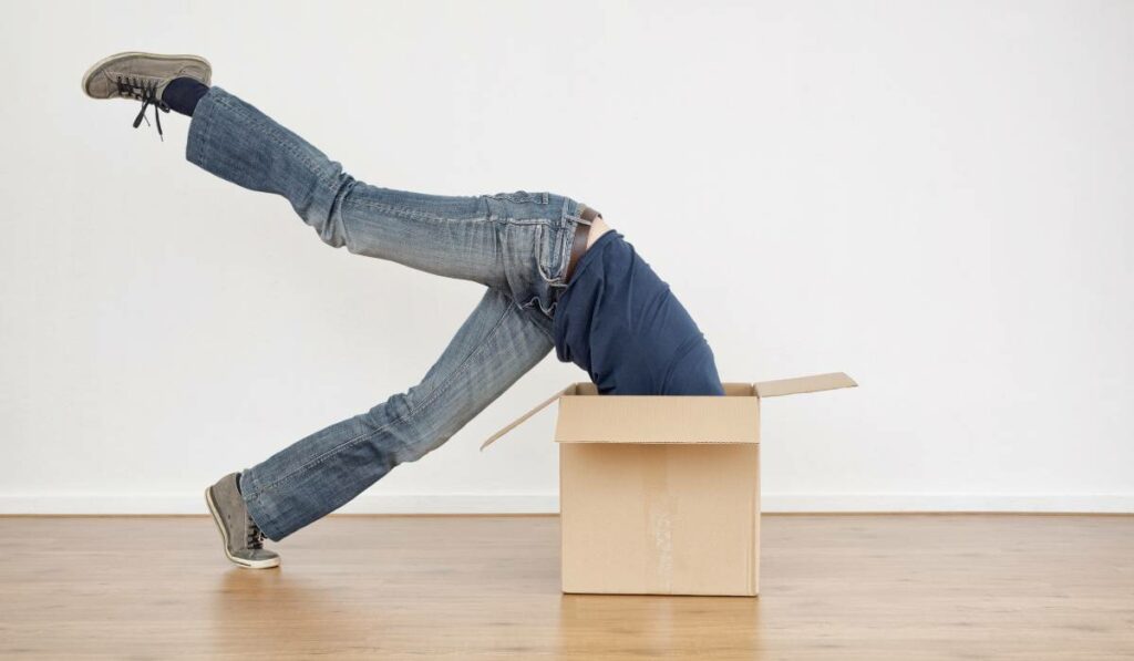 A woman performing a handstand in a cardboard box