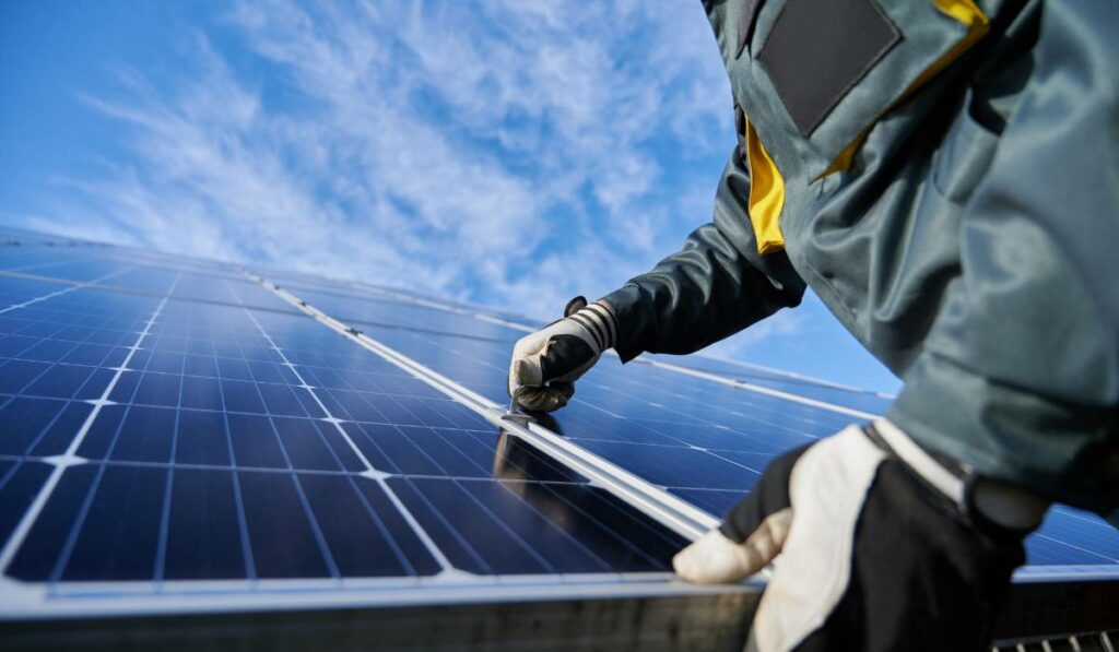 A person is working on a solar panel with a blue sky in the background