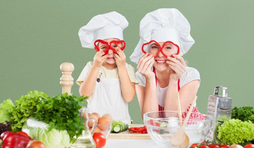 Mom and a child holding bell peppers in front of their eyes and smiling at the camera. There are vegetables and eggs placed on the table.