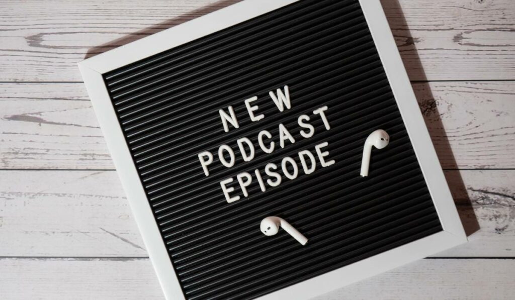 New podcast episode written on a board with ear pods lying around