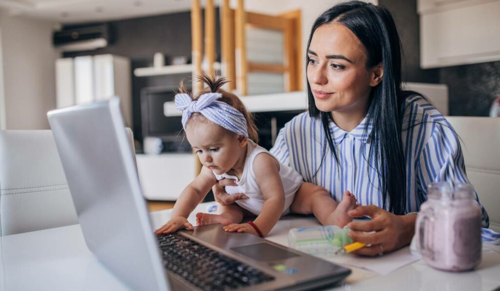 a mother and a baby are sitting at a table with a laptop