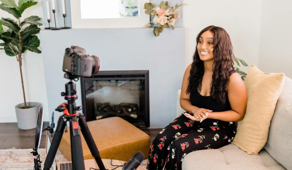 a woman is smiling while sitting on a couch in front of a camera