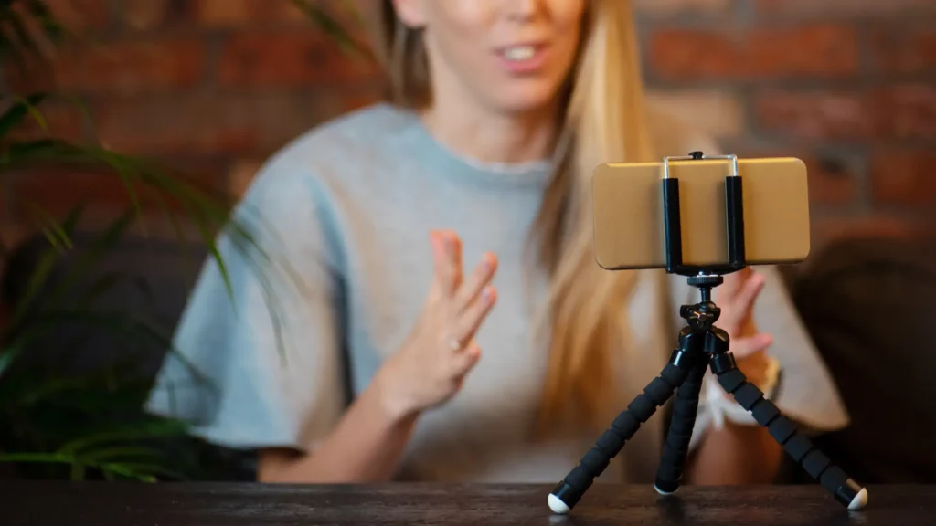 a woman is sitting in front of a tripod with a cell phone on it