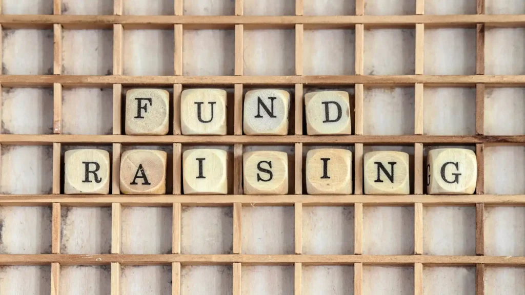 the word fund raising in wooden letters