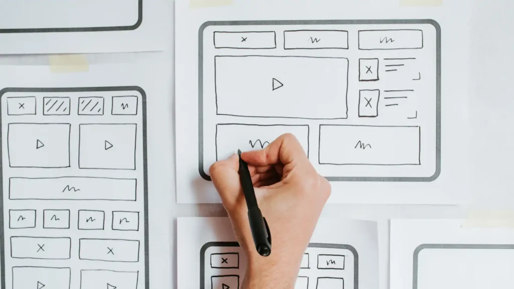 a person is drawing a website sketch on a whiteboard with a pen