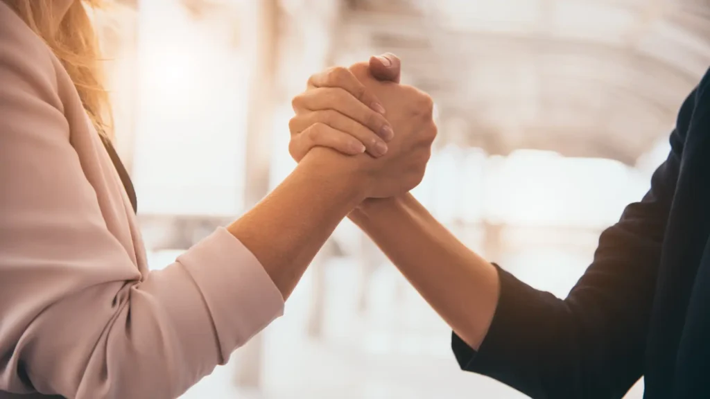 Two individuals shaking hands in an office building